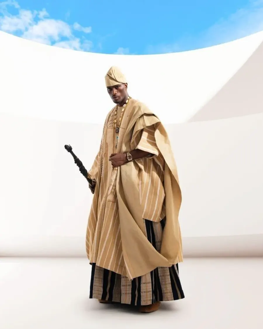 A gold striped agbada worn full length with a matching cap